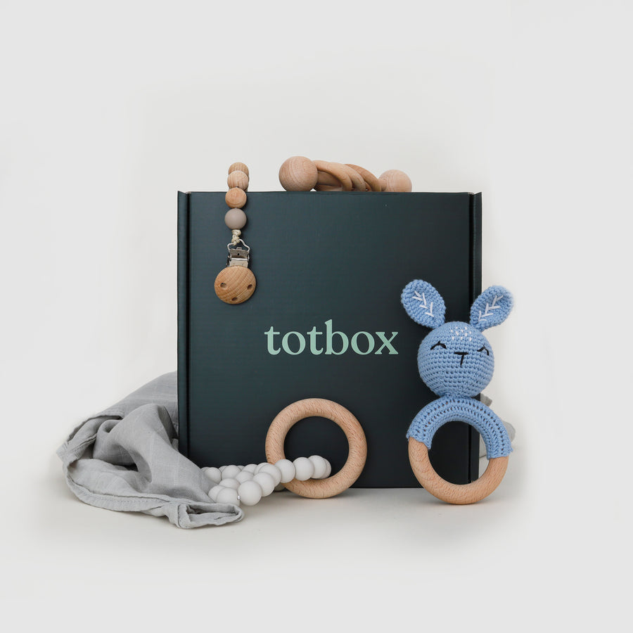 This is a baby gift box. It has a wooden rattle, silicone teether, handmade crochet rattle, pacifier clip, and organic cotton swaddle.